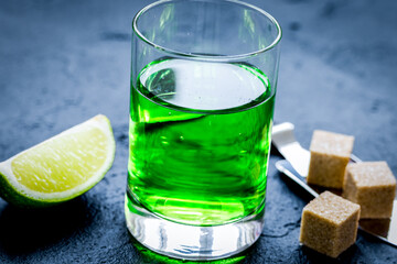 absinthe with sugar cubes in spoon on dark background