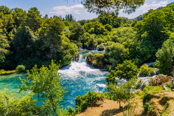 Fototapeta na wymiar A view of amazing waterfalls and houses in the forest inside Krka National Park, Dalmatia, Croatia