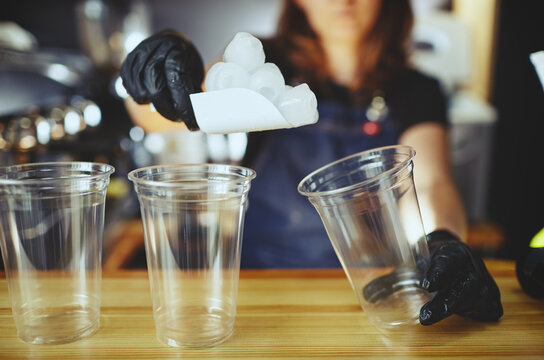 Bartender wearing medical latex black gloves, making mojito cocktail.Pieces of ice,ingredient for cooling drinks in bar.Blurred image, selective focus