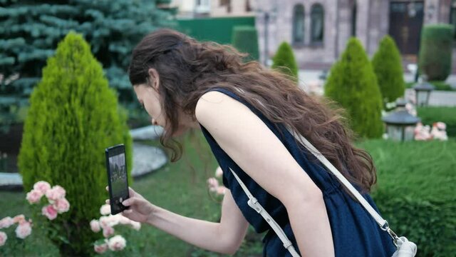 portrait woman in garden taking pictures on phone pretty flowers or rare plants