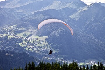 Paragliding among the mountains on sunny summer day. Paraglider flight against beautiful mountains...