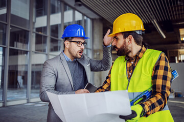 Frustrated architect yelling at contractor because he made mistake. Building in construction...