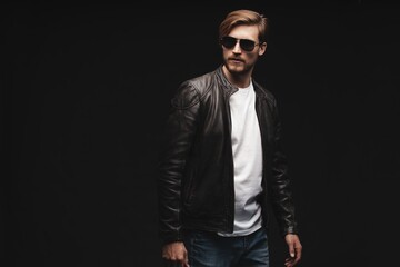 Fashion man, Handsome serious beauty male model portrait wear sunglasses and leather jacket, young guy over black background