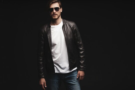 Fashion man, Handsome serious beauty male model portrait wear sunglasses and leather jacket, young guy over black background