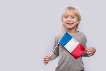 Exciting fair-haired boy holding flag of France. Learning French for children. Education in France.