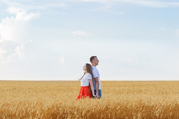 Naklejka na ściany i meble Young couple standing in wheat field back to each other. Support in family