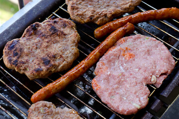 Traditional serbian barbecue (rostilj)  homemade sausages and burgers. Preparing a barbecue on a grill, outdoor roasting meat. Traditional Balkan cuisine, close up, top view 