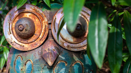 Rusty Metal Owl in Bushes Hiding Behind Leaves