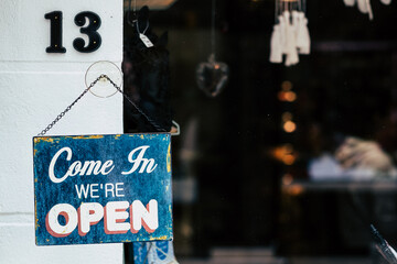 Plaque enn métal vintage bleu suspendu à une porte avec texte come in we're open