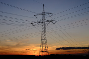 Strommast mit Kabeln vor Sonnenuntergang