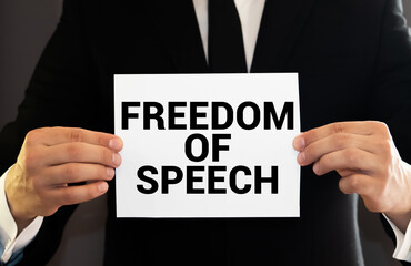 Unrecognizable male activist holding a placard with freedom of speech inscription while taking a part in protest against vaccination.