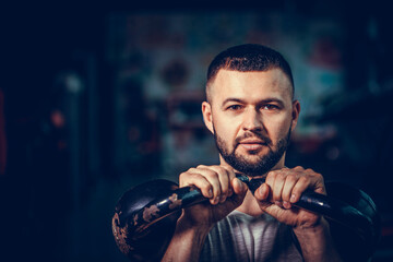 Bearded fitness man doing a weight training by lifting heavy kettlebell. Yong athlete doing kettlebell swings. Bodybuilder lifting with kettlebell.