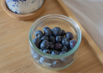 Bowl of fresh Blueberries on wooden tray in bed.