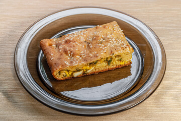  piece of homemade pie with green onions and eggs on a glass plate close up