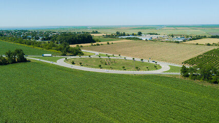 Aerial view of highway traffic circle between meadow and agricultural field.
