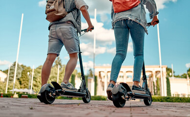Cropped image of students riding electric scooters. A guy and a girl on scooters ride along the city road. © Valerii Apetroaiei