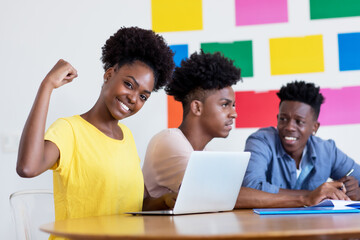 Cheering african american female student at computer with group of students