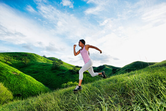 Black athlete running on rural hillside