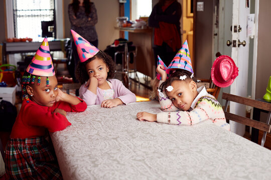 Bored children wearing party hats at table
