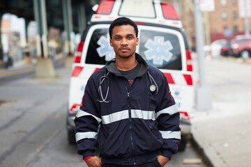 Portrait of young man standing in front of ambulance on street
