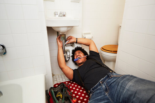 Mixed race man fixing sink plumbing