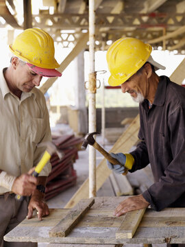 Hispanic workers using hammers at construction site