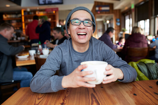 Portrait of mature man holding coffee cup while sitting in coffee shop