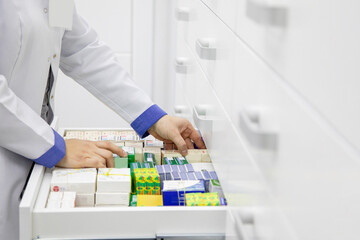 Pharmacist holding medicine box and capsule pack in pharmacy drugstore.