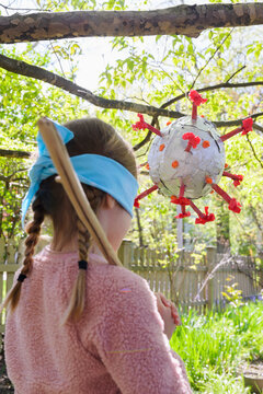 Girl (6-7) preparing to hit coronavirus shaped pinata