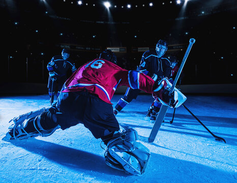 Hockey goalie in defensive position against forwards