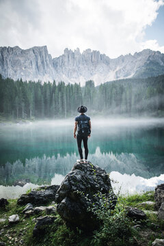 Young man standing by Lake Carezza during sunrise