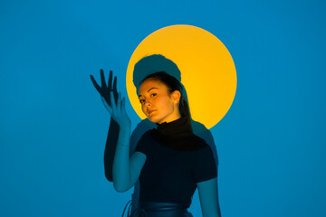 Young woman moving in blue light in front of yellow circle