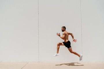 Barechested male athlete jumping at a wall