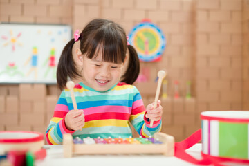 toddler girl play xylophone at home for homeschooling