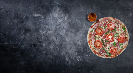 Fototapeta na wymiar Unbaked pizza with ham on dark background