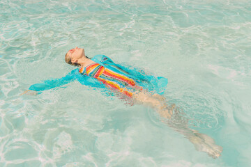 Dressed woman floating on water in swimming pool