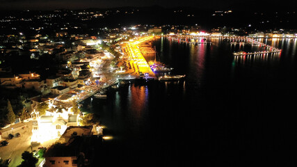 Fototapeta premium Aerial drone night shot of picturesque illuminated promenade area of Porto Heli fjord village, Argolida, Peloponnese, Greece