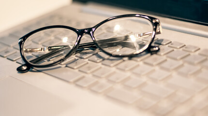 Eye glasses on office computer keyboard,Close up eye glasses, office computer, Gray tone,fashion...