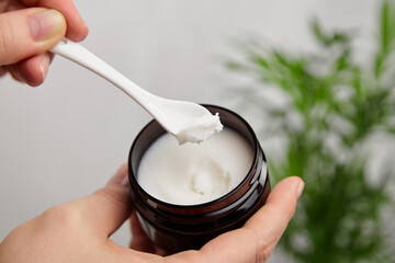 Dark jar with organic pure shea butter base oil in female hand. Natural cosmetics.