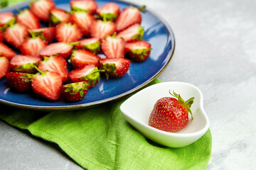 Ripe red strawberries on ceramic plates on grey concrete table background.