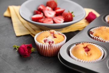 Strawberry muffins with fresh ripe berries on black concrete background