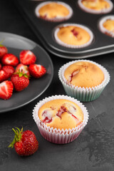 Two strawberry muffins with fresh strawberry berries on dark grunge background