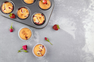 Strawberry muffins with fresh berries and flowers on gray concrete background