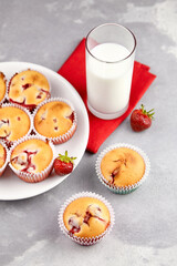 Healthy dessert - strawberry muffins with glass of fresh milk on grey concrete background