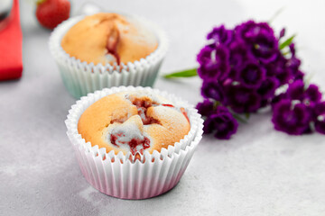 Strawberry muffins with fresh flowers on grey concrete background