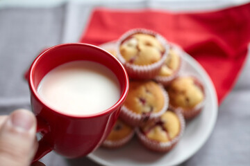 Cup of milk in hand with strawberry muffins, sweet summer dessert