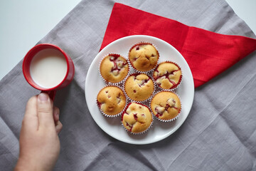 Homemade summer pastry - strawberry muffins with cup of milk on kitchen table, flat lay
