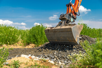 A small excavator is building a new road on a green field. copy space
