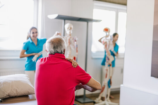 Female physiotherapist explaining treatment to patient, using skeleton
