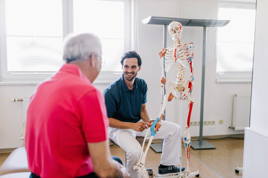 Physiotherapist explaining treatment to patient, using skeleton